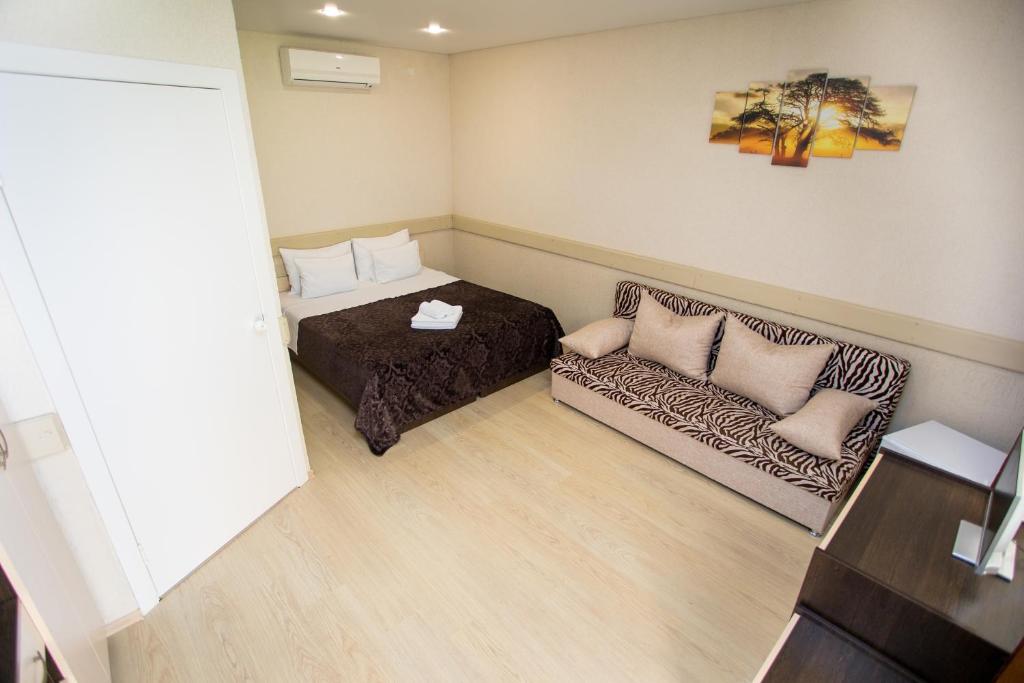 アナパにあるGuest House on Azovskaya 21のベッド1台とソファが備わる小さな客室です。
