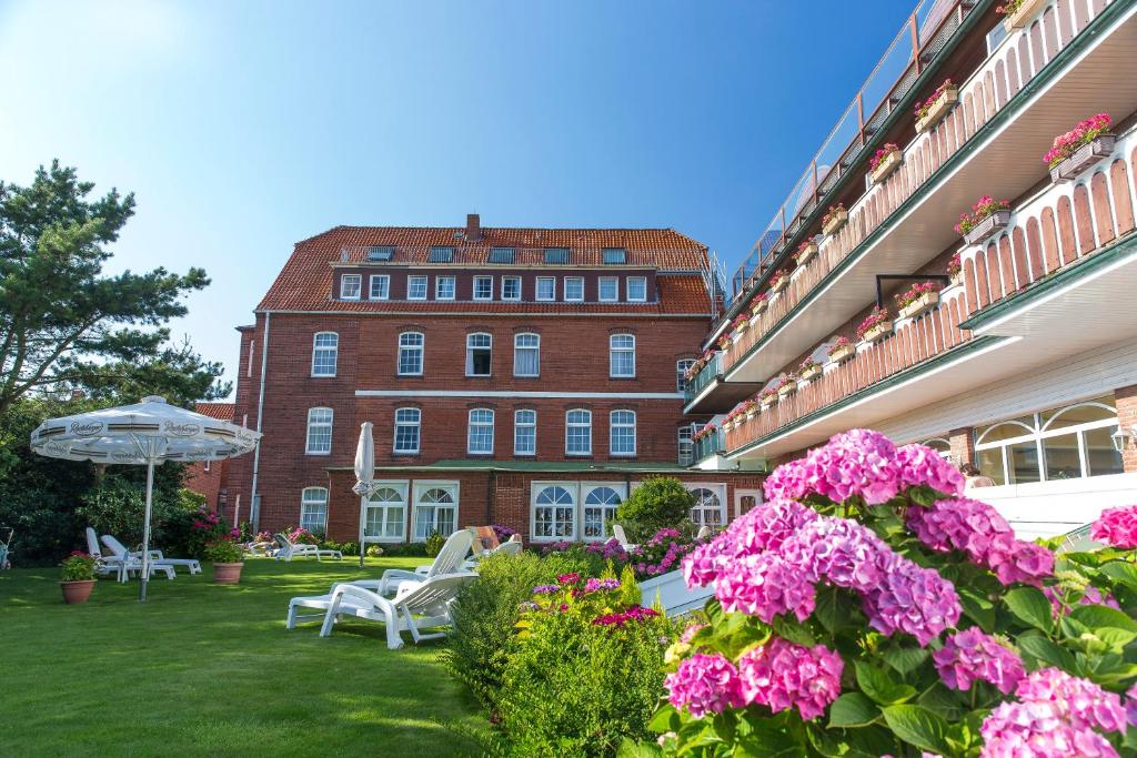 a courtyard with pink flowers and a building at Nordseehotel Freese in Juist