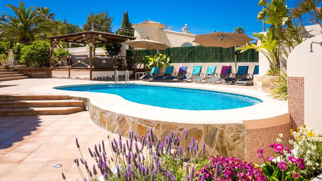 - une piscine dans une cour agrémentée de parasols et de fleurs dans l'établissement Casa Los Pinos, à Benissa