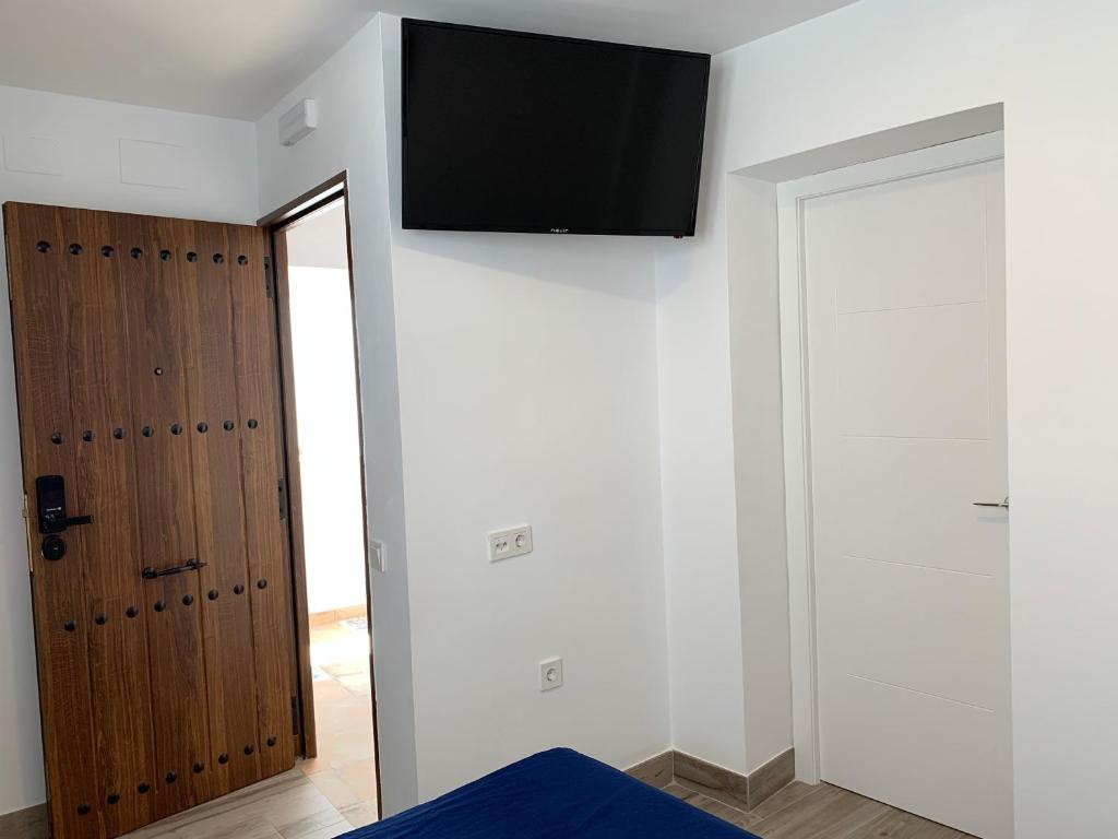 Habitación con TV en la pared y puerta en Belmonte Rooms, en Córdoba