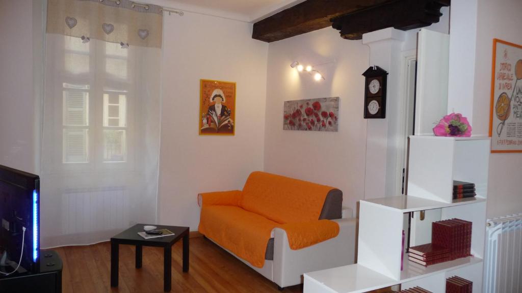 - un salon avec une chaise orange et une télévision dans l'établissement La casa di Perpy Ivrea centro storico, à Ivrea