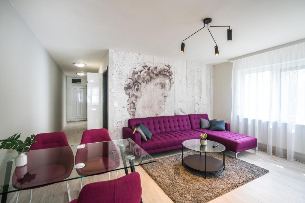 a living room with a purple couch and chairs at Sprint Apartman in Siófok