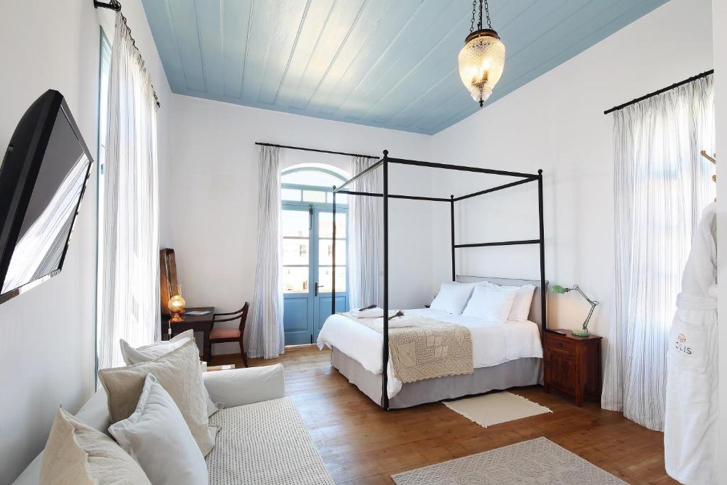 a bedroom with a canopy bed in a white room at Polis 1907 by Louis Hotels in Polis Chrysochous
