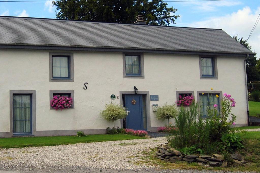 a white house with a blue door and flowers at Gîtes Les Myosotis in Morhet