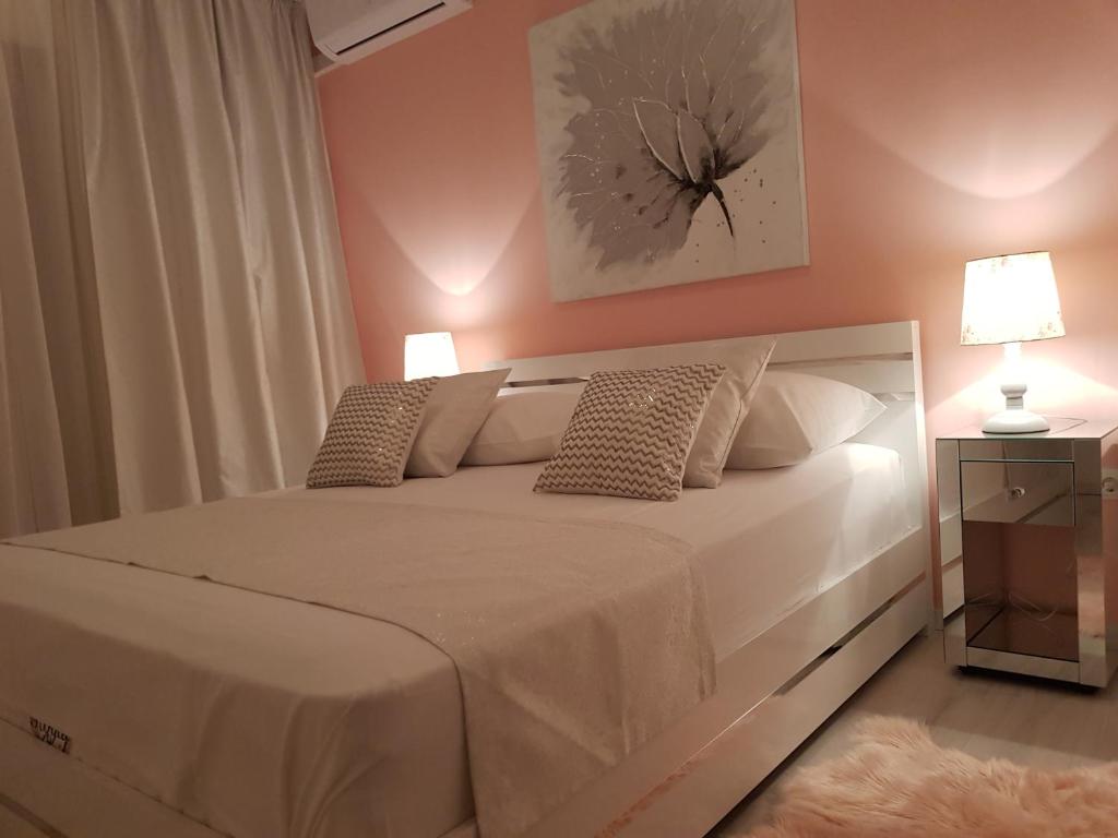 a bedroom with a large white bed with two pillows at APARTMAN KSENIJA KOVAČIĆ in Stanići