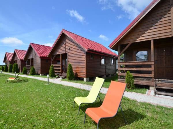 a group of chairs sitting in the grass in front of buildings at Domki Letniskowe WIKTORIA in Jezierzany