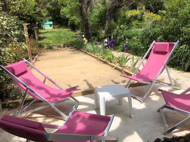 3 chaises roses et une table blanche sur une terrasse dans l'établissement Aniane Maison Renovee avec Jardin et Boulodrome, à Aniane