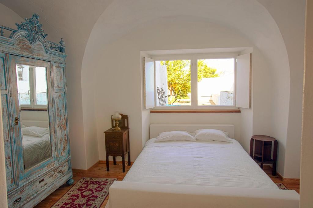 a bedroom with a bed and a window and a mirror at CASA AMARELA in Avis