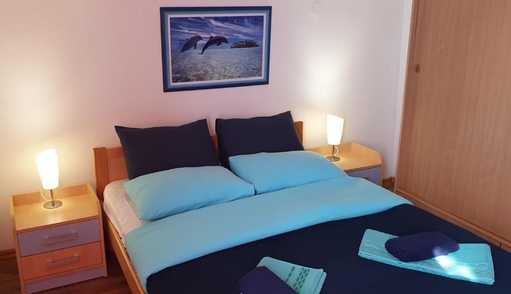 1 dormitorio con 1 cama con sábanas azules y 2 lámparas en Adriatic, en Orebić