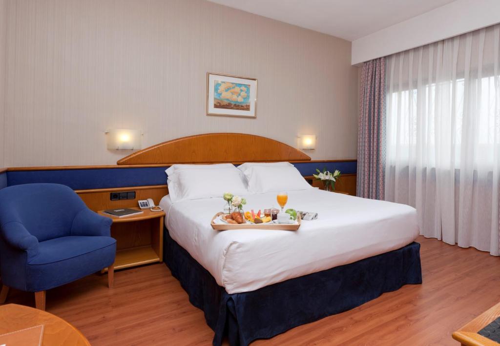a hotel room with a large bed and a blue chair at Agumar in Madrid