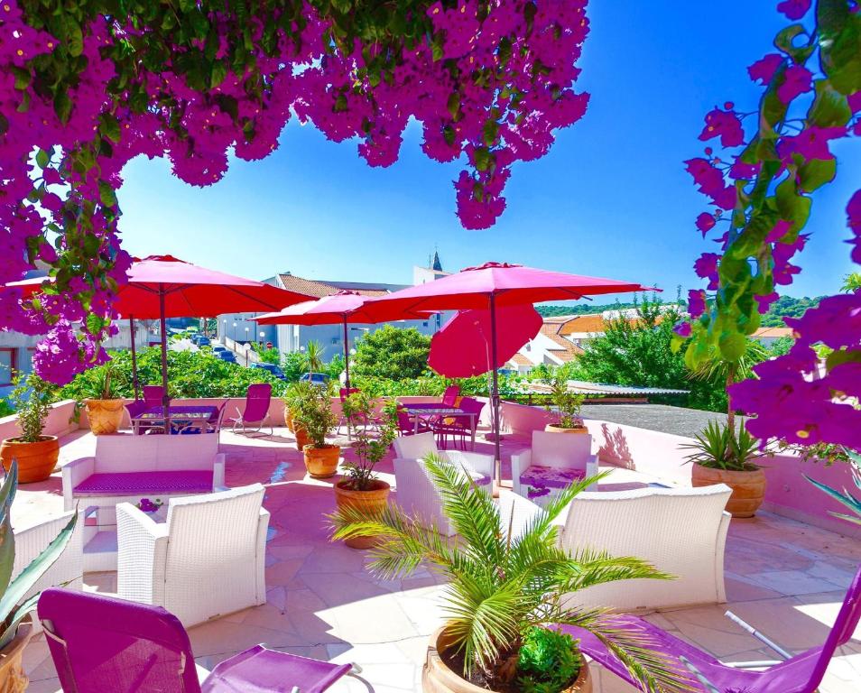 un patio con sombrillas rojas, sillas y plantas en Luxury Apartments Marhella & Jakov en Makarska