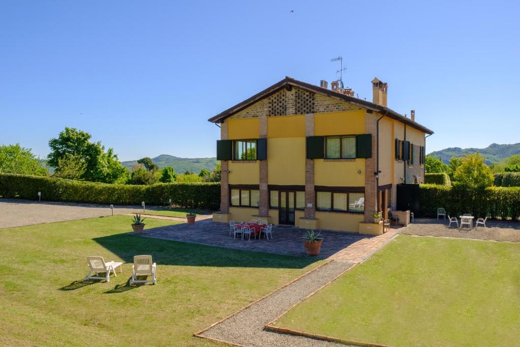 a house with a yard with chairs and tables at La Quercia - BolognaRooms in Sasso Marconi
