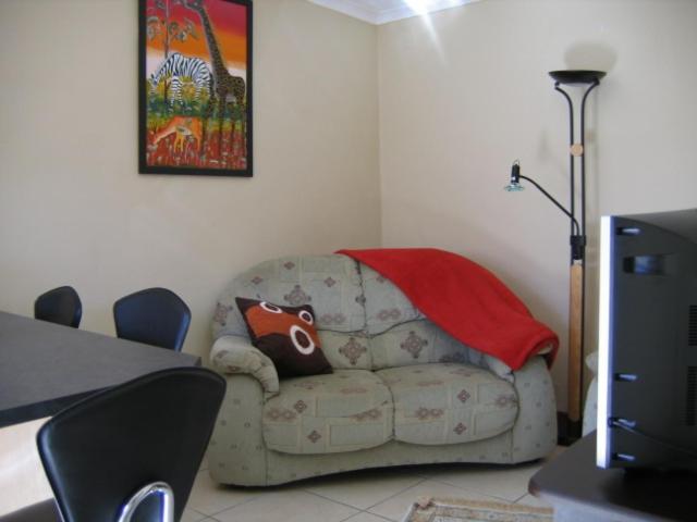 sala de estar con sofá y manta en Malleson Garden Cottage, en Ciudad del Cabo