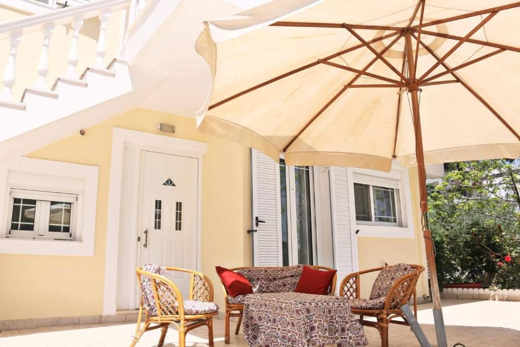 eine Terrasse mit einem Tisch, Stühlen und einem Sonnenschirm in der Unterkunft Entire large house Apollon in Voládha