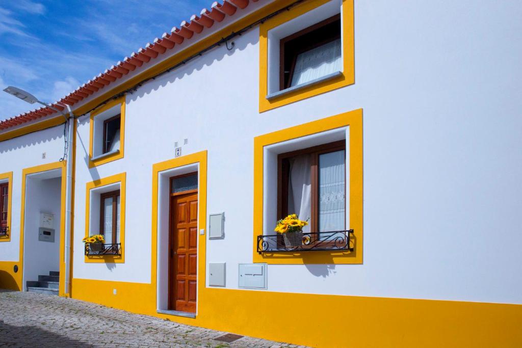 una casa blanca y amarilla con flores en la ventana en A Casa dos Girassóis en Cuba