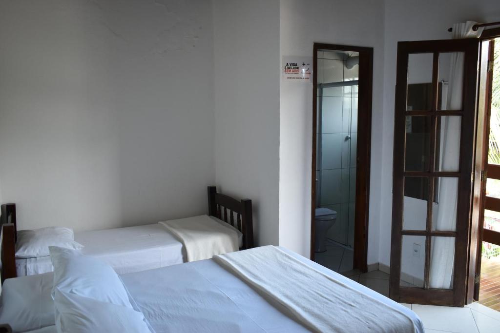 a bedroom with two beds and a door to a bathroom at Pousada Cores Do Mar in Paraty