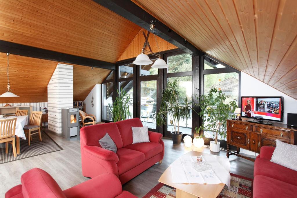 a living room with red couches and a tv at Haus Sonnenhügel in Winterberg