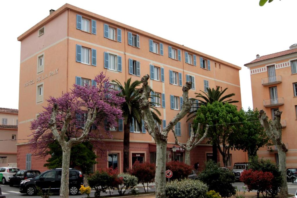 a large building with trees in front of it at Hotel de La Paix in Corte