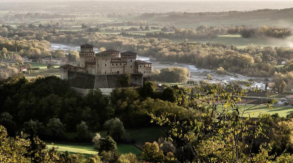 um castelo no topo de uma colina com árvores em La Locanda del Borgo em Torrechiara