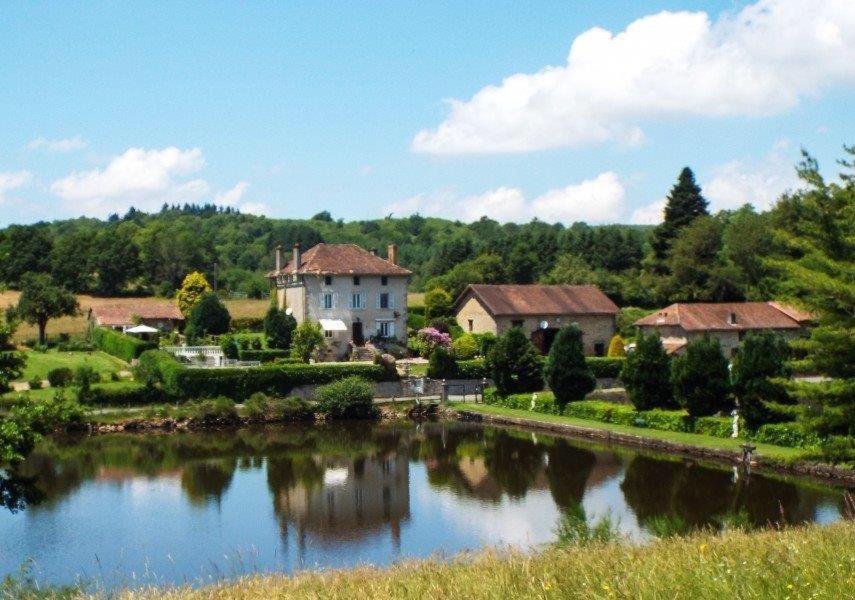 ein Haus auf einem Hügel neben einem Fluss in der Unterkunft La Vieille Maison D'Aurin in Bussière-Galant