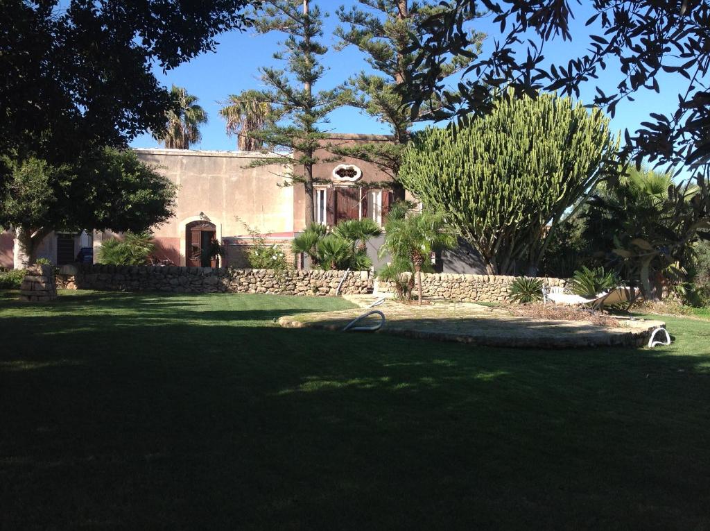 una casa con un cortile alberato e prato di Campo Reale country rooms a Pachino