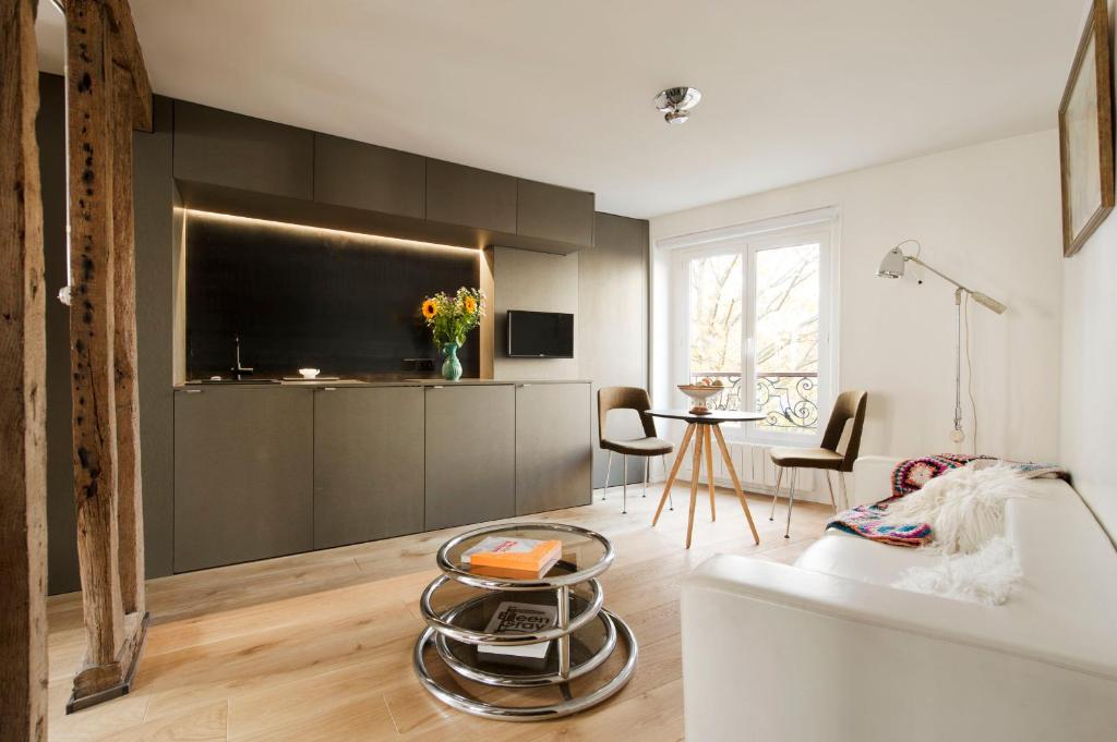 un salon avec un canapé blanc et une télévision dans l'établissement Le Marais Calme et lumineux, à Paris