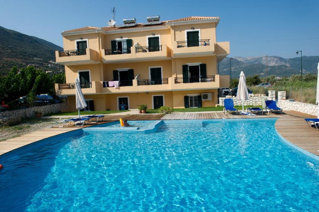 a villa with a swimming pool in front of a house at Calypso Luxury Studios in Vasiliki