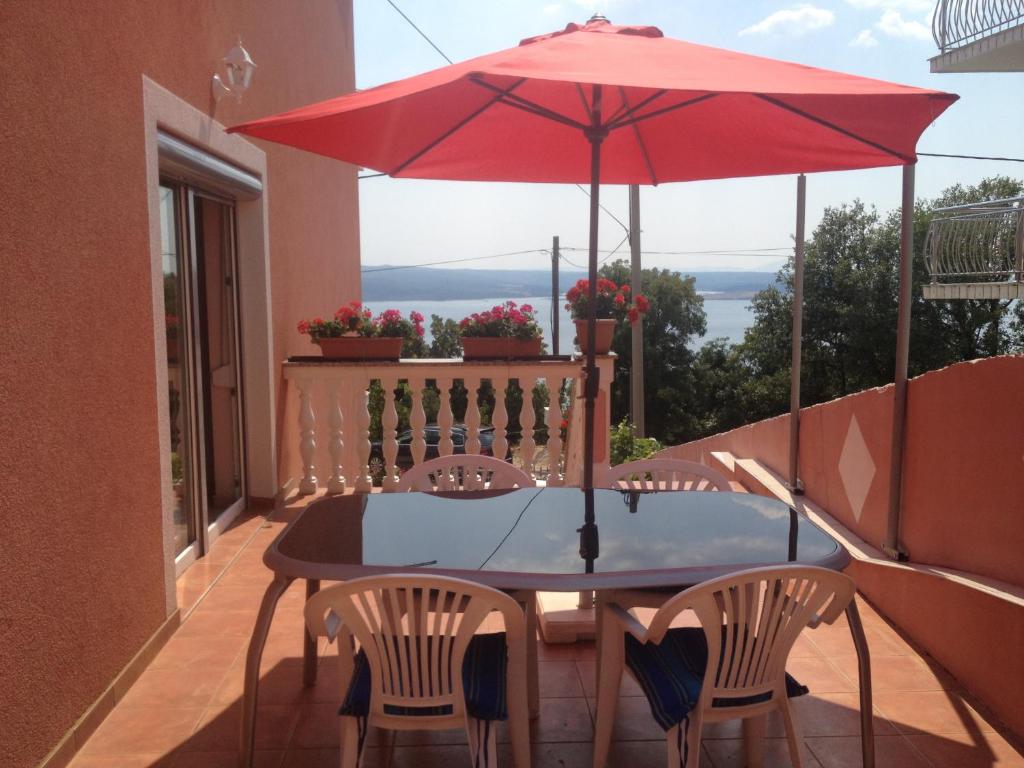 a table and chairs on a balcony with a red umbrella at Villa Mirjana in Dramalj