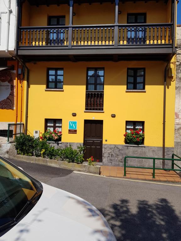 a yellow building with a balcony on a street at Casa Belarmina in Cangas de Onís