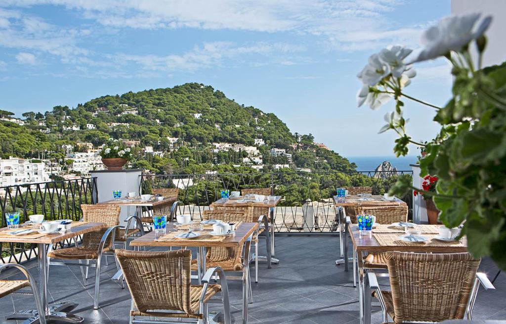 a patio with tables and chairs and a mountain at Hotel La Tosca in Capri