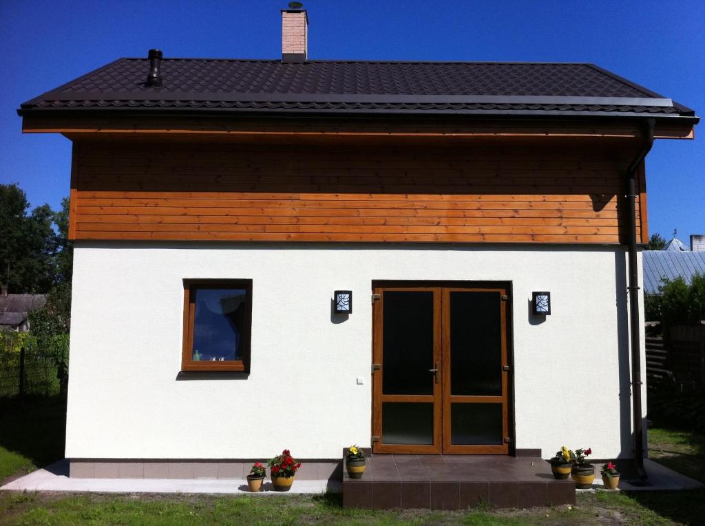 una pequeña casa blanca con puerta marrón en Guest House Grāvju 11, en Jūrmala