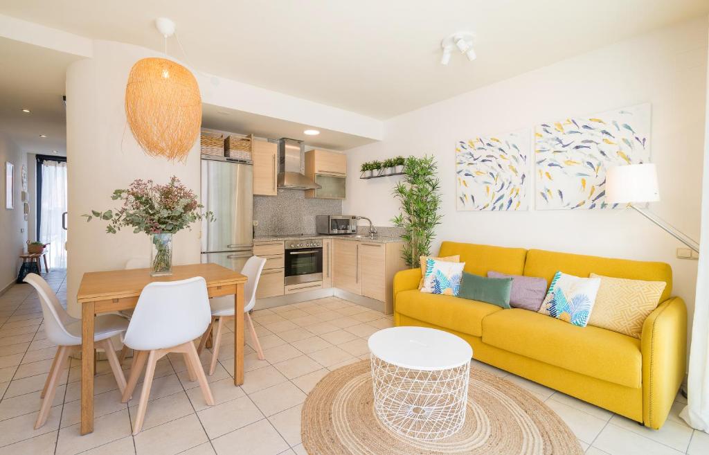 a living room with a yellow couch and a table at Beach Apartment in the heart of Tamariu in Tamariu