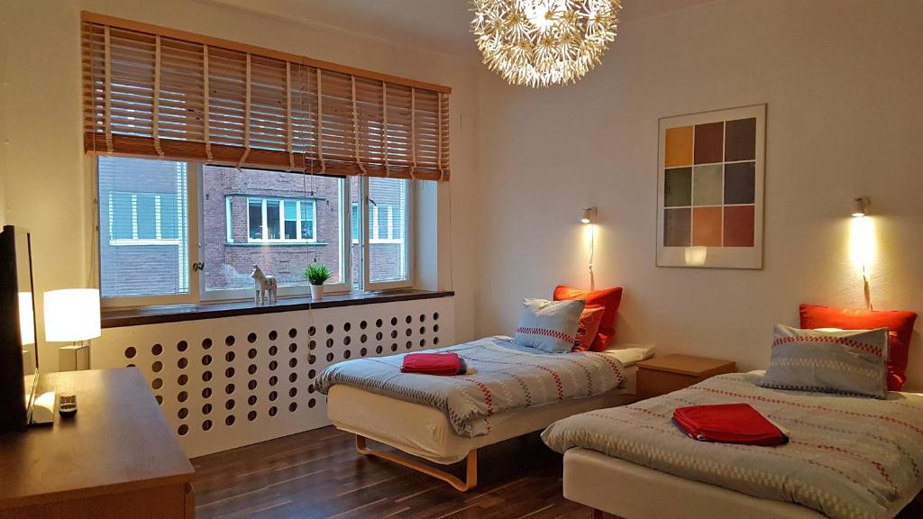 Un dormitorio con 2 camas y una ventana con una lámpara de araña. en City Apartments Triangeln, en Malmö