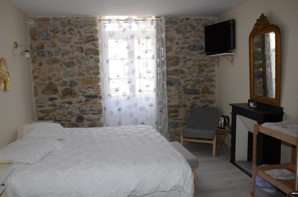 a bedroom with a bed and a stone wall at Nostra Demora in Quillan
