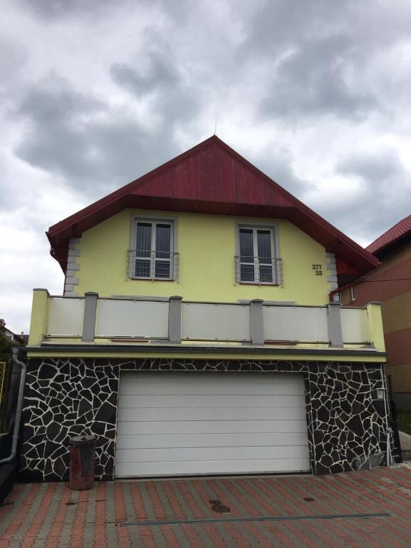 una casa amarilla con garaje con techo rojo en Privát Daniela Štrba en Štrba