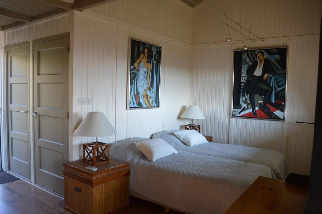 a bedroom with a bed with two lamps and two pictures at Les mésanges du Domaine du Moulin 31 in Trollat