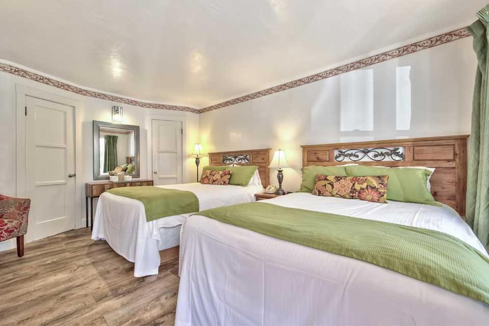 a bedroom with two beds with green and white sheets at Silver Maple Inn and The Cain House Country Suites in Bridgeport