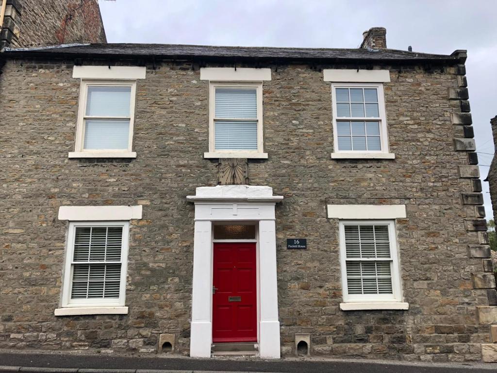 um velho edifício de tijolos com uma porta vermelha em Pinfold House em Richmond