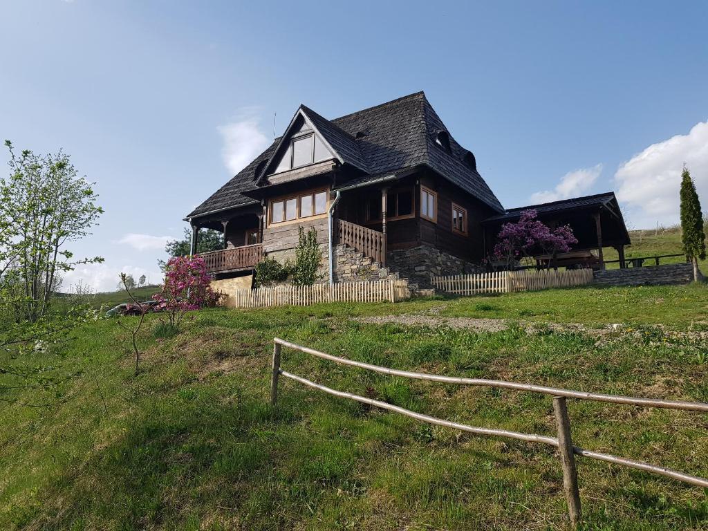 ein Holzhaus auf einem Hügel mit einem Zaun in der Unterkunft Ninga Rai in Poienile Izei