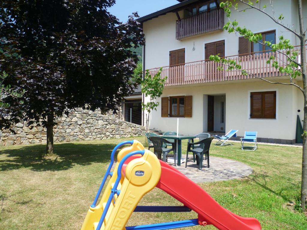 a slide in a yard with a table and a house at Casa Vacanza Ca dei Logi in Levico Terme