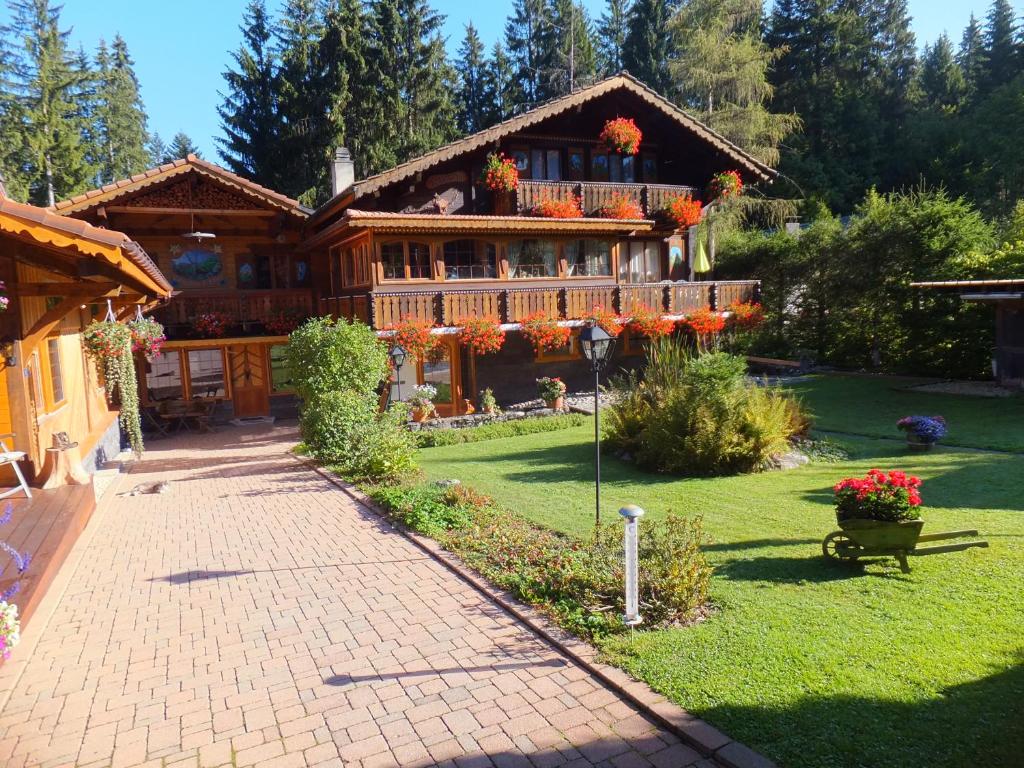 a large wooden house with flowers on it at Au Petit Gîte Les Paccots in Châtel-Saint-Denis