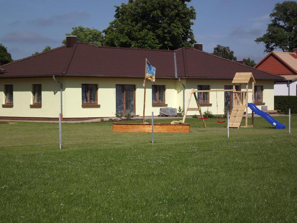 a house with a playground in the yard at Ferienhaus bei Familie Gau in Schaprode (Ortsteil Poggenhof) in Schaprode