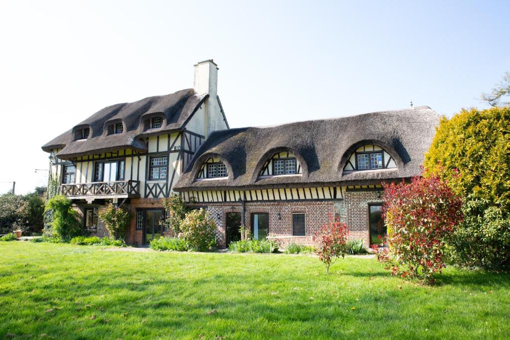 una casa grande con techo de gambrel en un campo verde en Les Hauts d'Etretat en Bordeaux-Saint-Clair