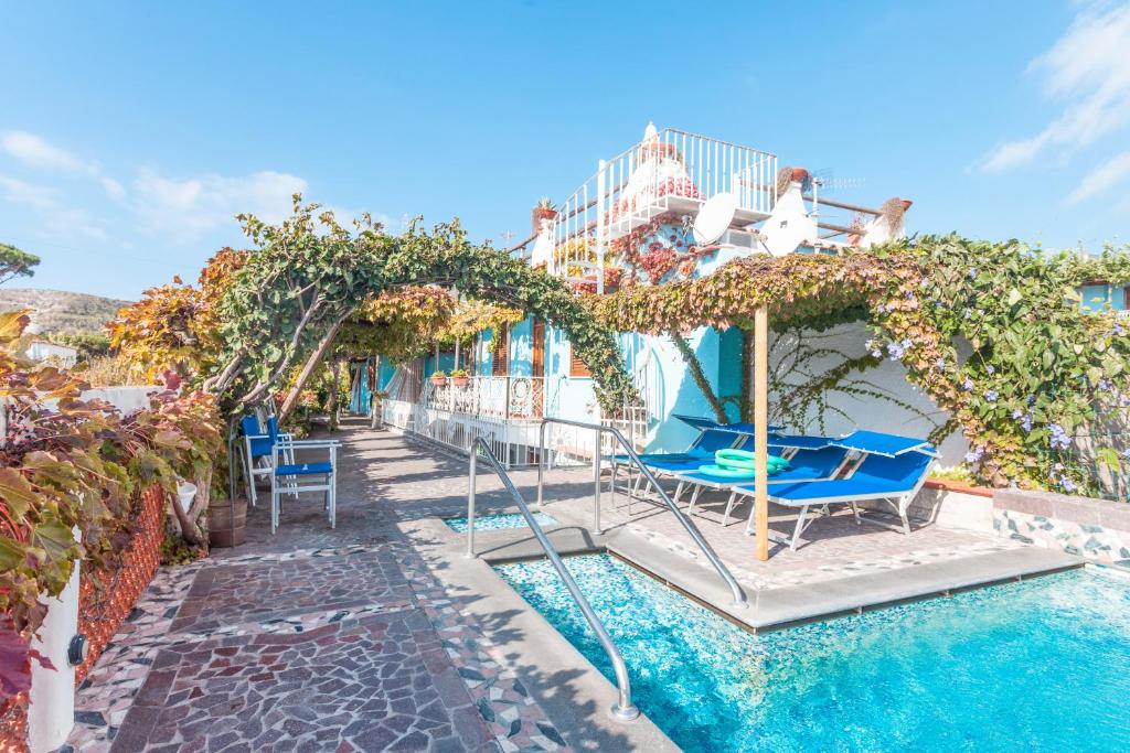a resort with a swimming pool with chairs and an umbrella at Hotel Casa Giuseppina in Ischia
