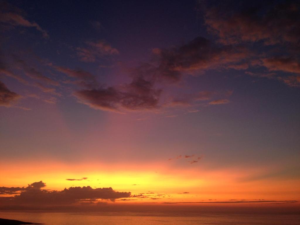 a sunset over the ocean with a cloudy sky at Casa do Cruceiro surfing Costa da Morte in Cayón