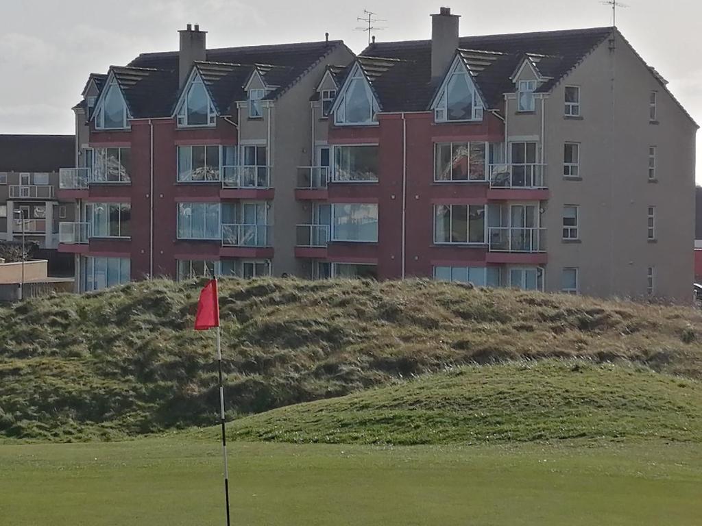 un gran edificio con bandera roja en un campo de golf en Links Vista Portrush en Portrush