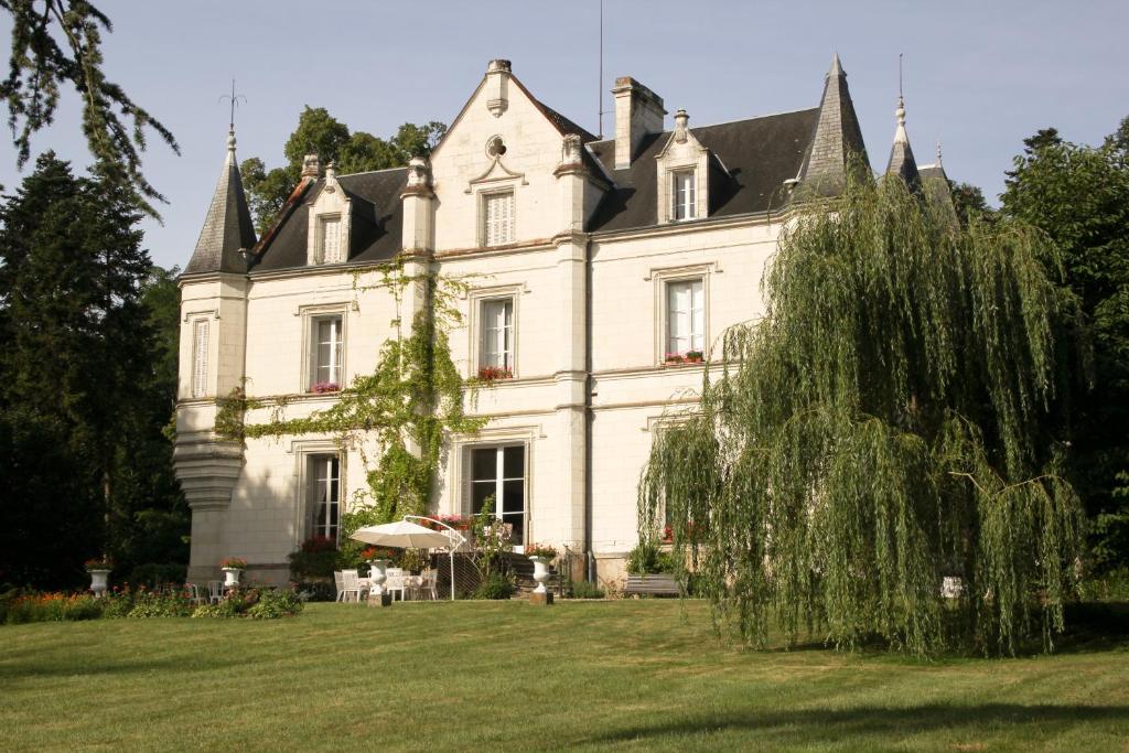 une grande maison blanche avec un arbre dans la cour dans l'établissement Château de Mont-Félix, à Saint-Jean-Saint-Germain