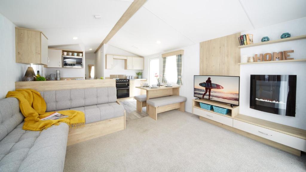 a living room with a couch and a flat screen tv at Modern mobile home premium pitch in Port Seton