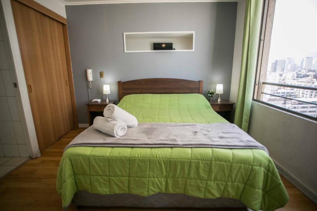 - une chambre avec un lit vert et une fenêtre dans l'établissement Apartments Zenteno, à Santiago
