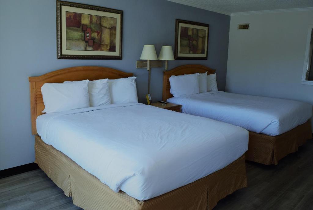 a hotel room with two beds with white sheets at Budget Inn Conway in Conway